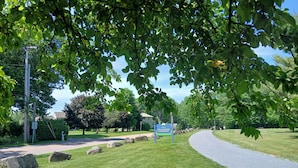 Un panneau indiquant la direction de Colchester Causeway, une route asphaltée, et une zone herbeuse avec des arbres.