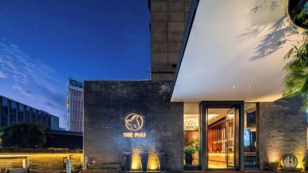 A hotel entrance with a modern design, featuring a prominent logo and a well-lit reception area. - THE PULI HOTEL (Hangzhou)