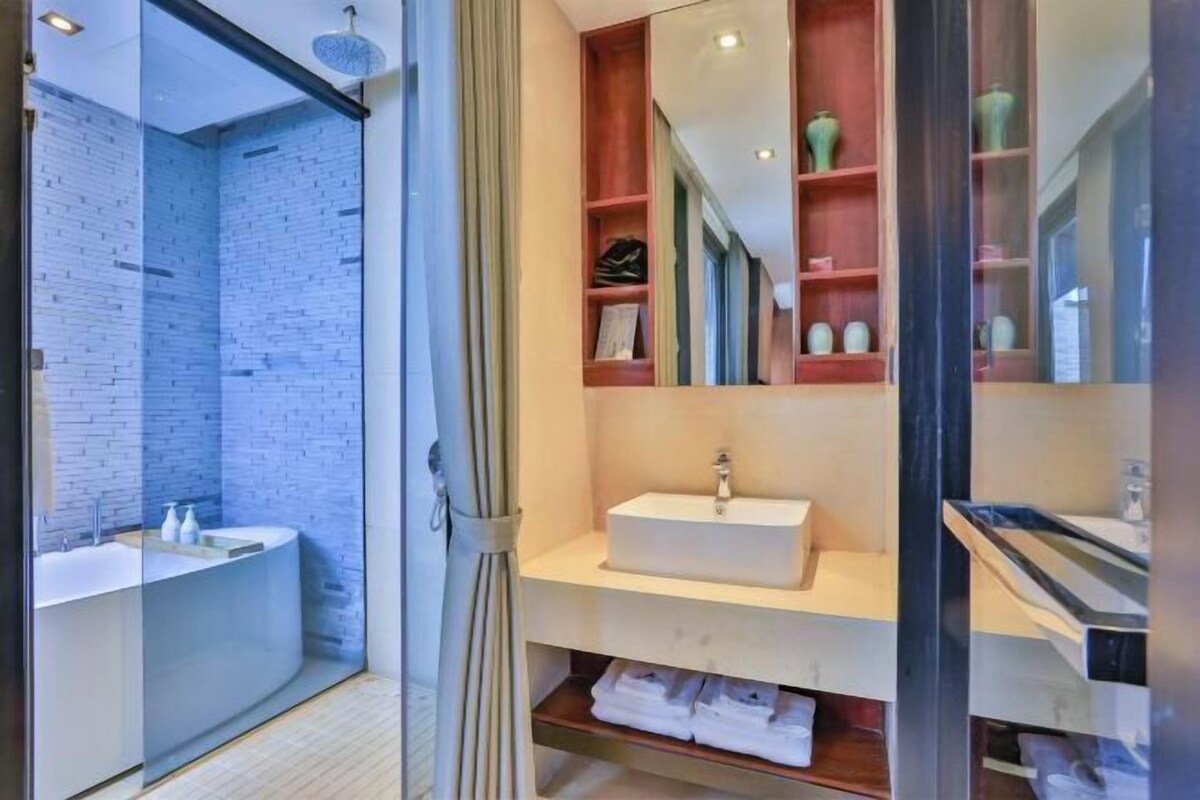 A modern bathroom with a glass shower enclosure, a white sink, and a vanity with shelves.