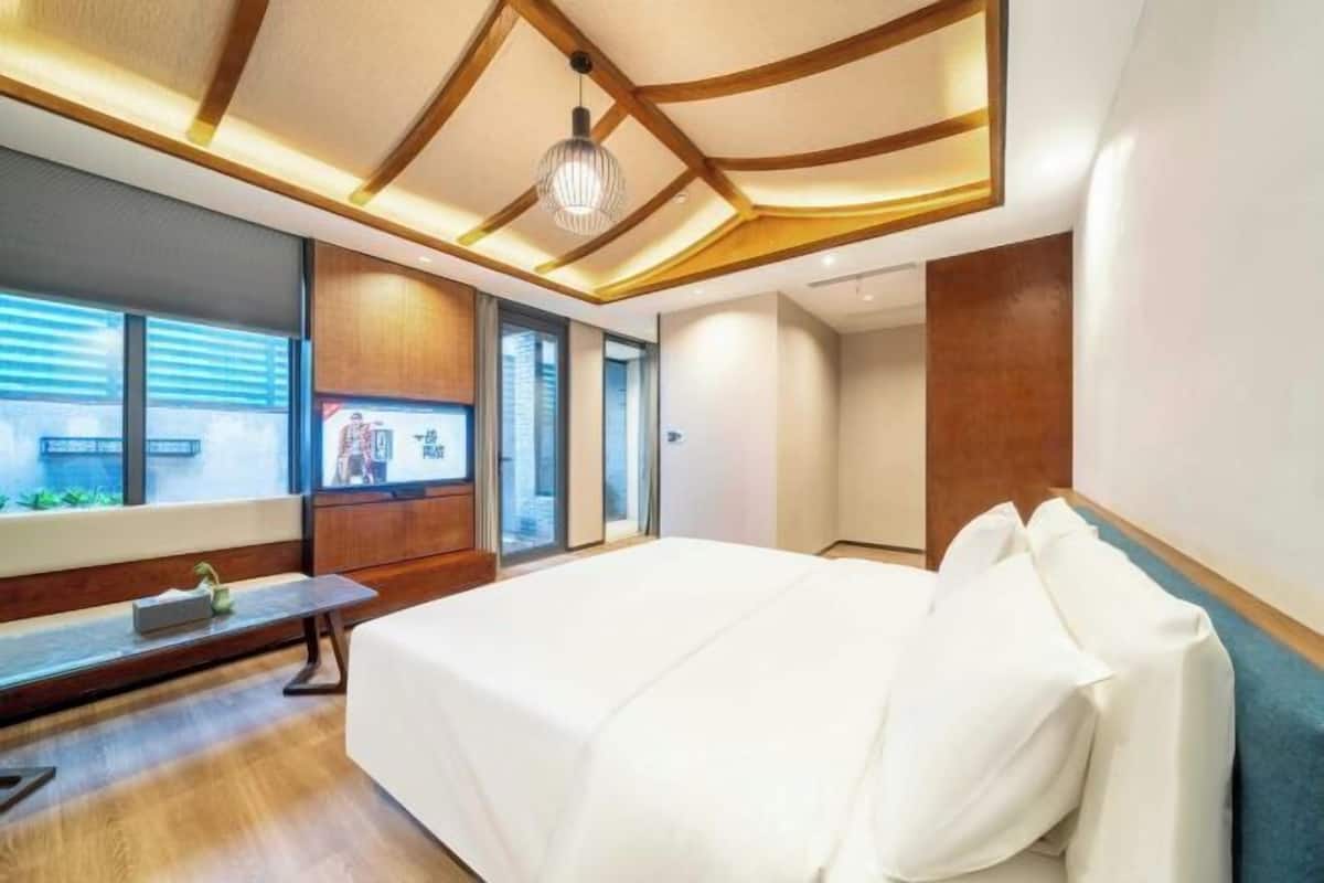 Una habitación de hotel moderna con una cama grande, vigas de madera en el techo y un banco junto a la ventana.