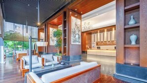 A modern hotel lobby with a reception desk, seating area, and large windows. - THE PULI HOTEL (Hangzhou)