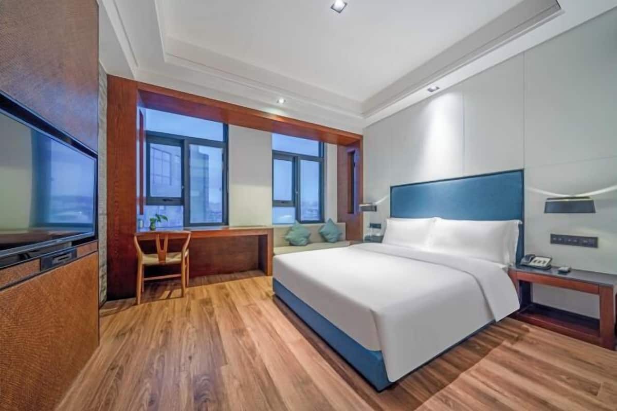 Una habitación de hotel moderna con una cama grande, un escritorio y un televisor.