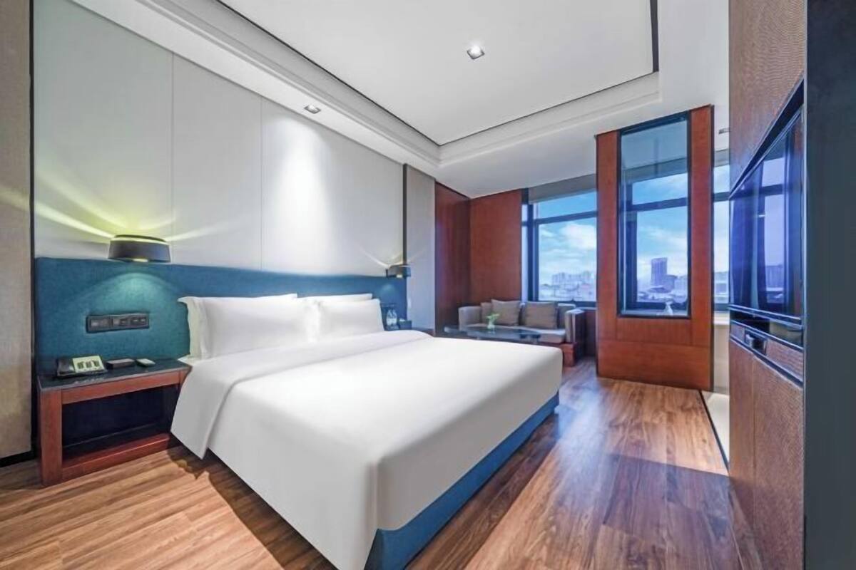 Una habitación de hotel moderna con una cama grande, un escritorio, una silla y vistas a la ciudad.