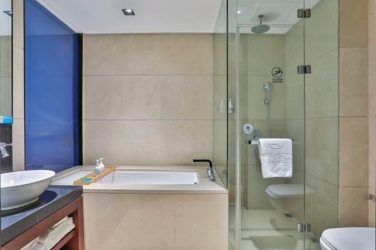 A modern bathroom with a glass-enclosed shower, a bathtub, and a sink with a mirror.