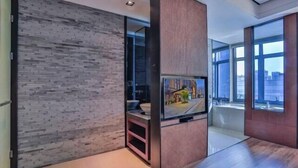 A modern living room with a flat-screen TV, a glass partition, and large windows. - THE PULI HOTEL (Hangzhou)