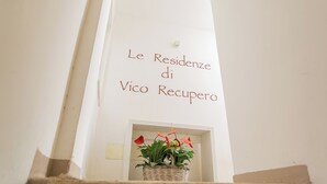 A white wall with the text "Le Residenze di Vico Recupero" and a wicker basket with red flowers. - Residenza Vico Recupero by Wonderful Italy (Polignano a Mare)
