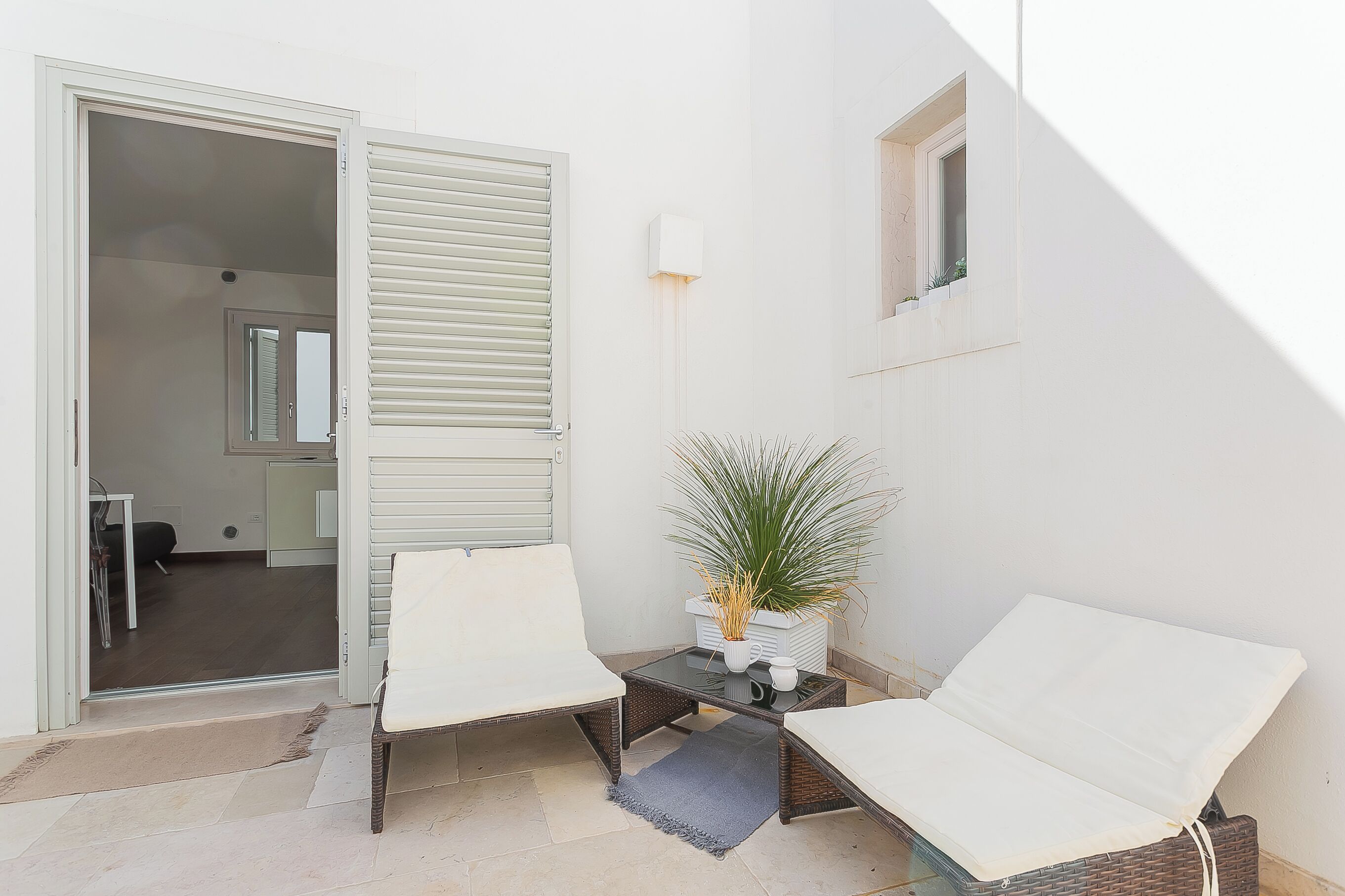 A small, open-plan living area with a sofa, a coffee table, and a potted plant.