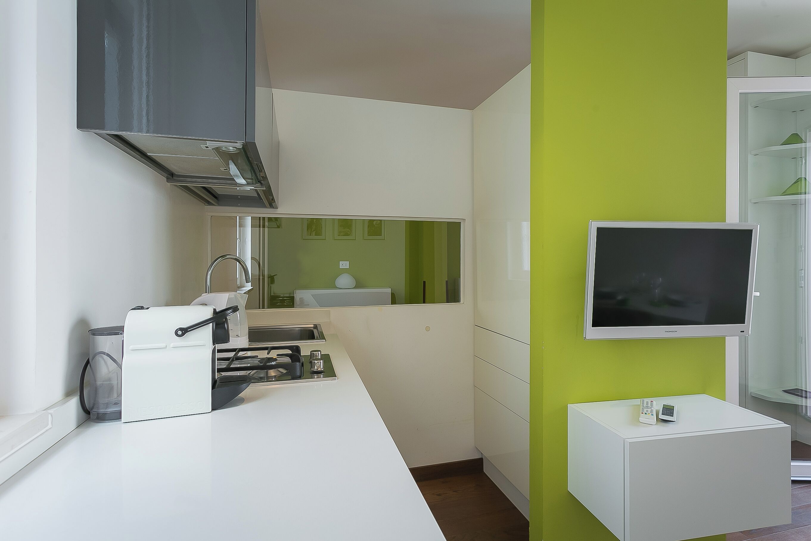 A modern kitchen with a built-in stove, a microwave, and a small cabinet.