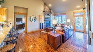 A spacious living area with a fireplace, wooden flooring, and a seating area with a sofa and chairs. - Cabin 75 Brasada Ranch + Hot Tub and Golf (Powell Butte)