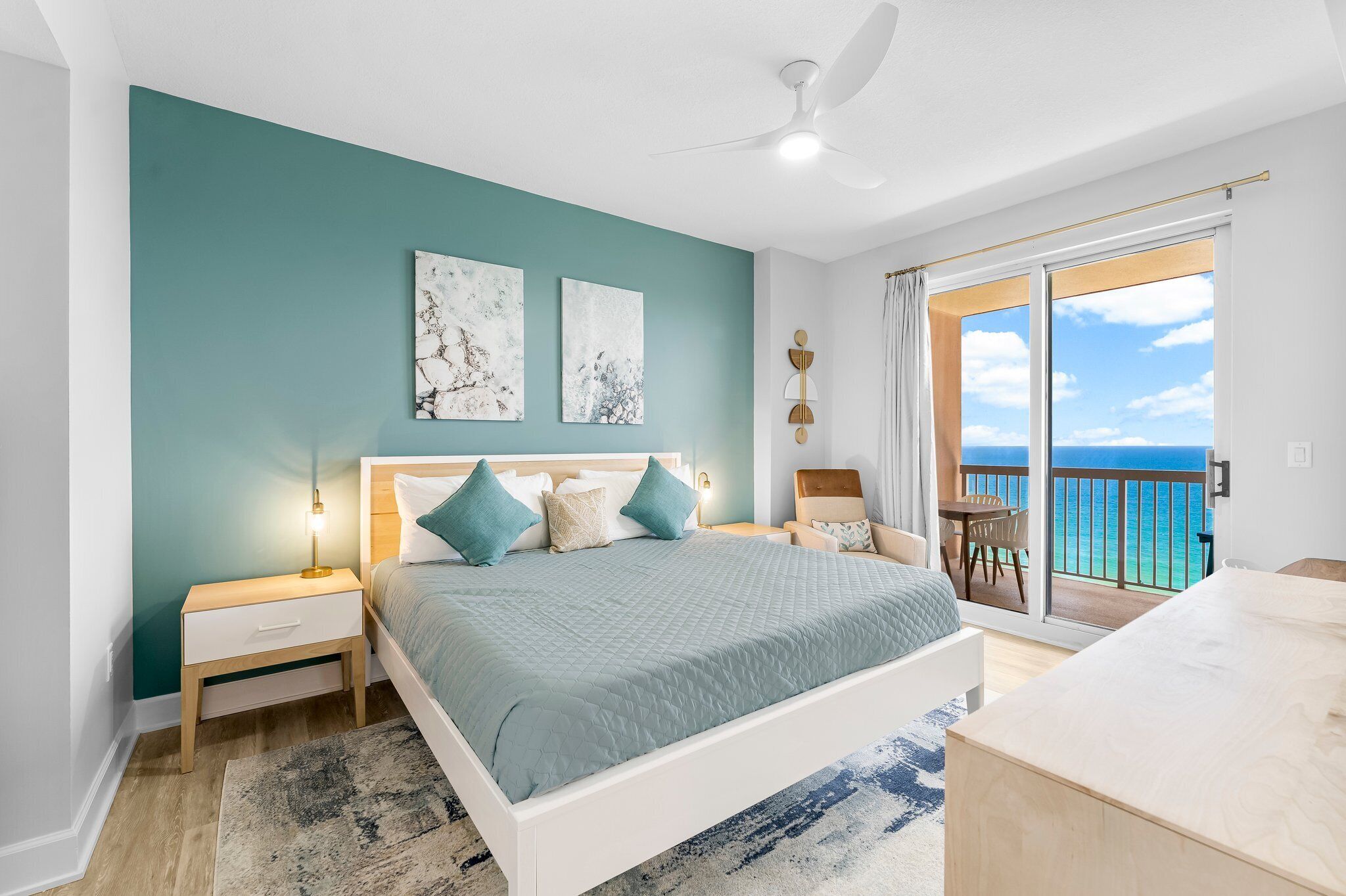 Une chambre à coucher comprenant un lit, une table de chevet, une chaise, une table et un balcon avec vue sur la mer.