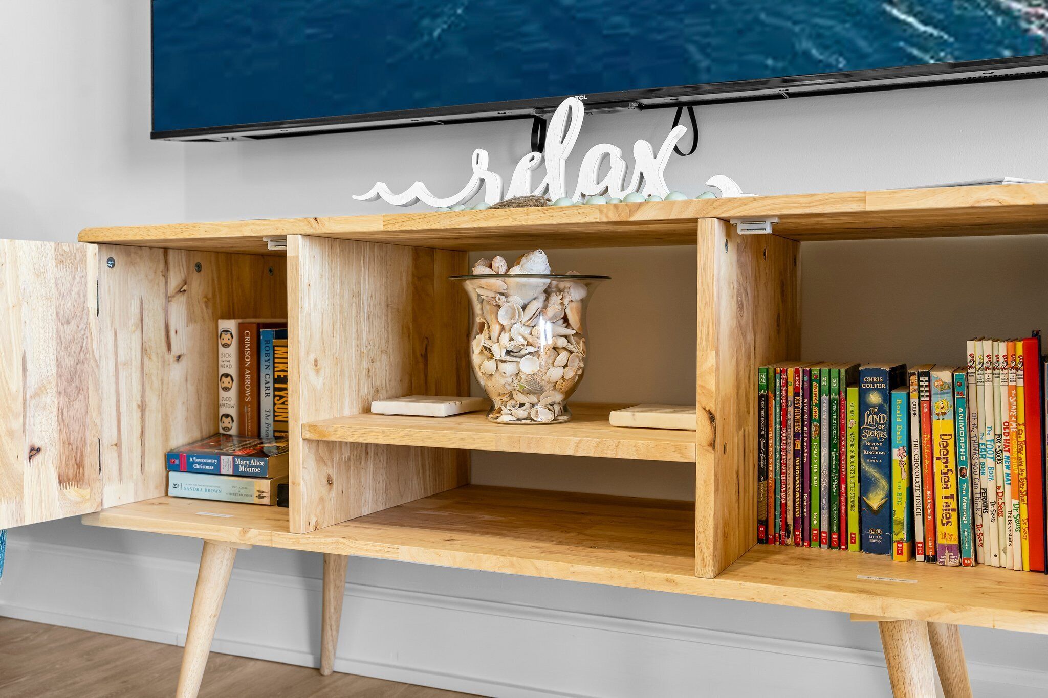 Una estantería de madera con libros y un jarrón decorativo.