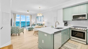 A modern kitchen with a central island, a dining area with a view, and a living room with a sofa and chairs. - Beachfront Family Escape • Beach Chairs Included (Panama City Beach)