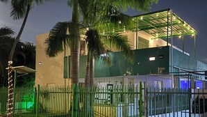 A gated property with a covered outdoor area, palm trees, and a building with a flat roof. - 3 Bedroom/2 Bathroom 1 block from the beach (San Juan)