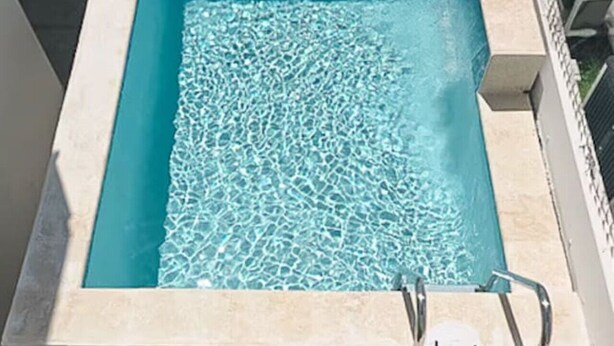 A rectangular pool with clear water, surrounded by a tiled deck and a metal ladder. - 3 Bedroom/2 Bathroom 1 block from the beach (San Juan)