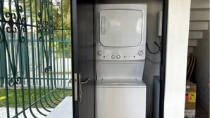 A compact laundry room with a washing machine and dryer, a metal gate, and a concrete bench. - 3 Bedroom/2 Bathroom 1 block from the beach (San Juan)