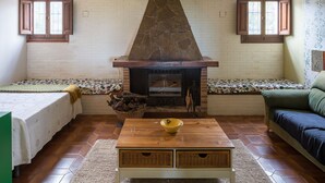 Un accogliente soggiorno con camino in pietra, un divano, un tavolino da caffè e una finestra con persiane.