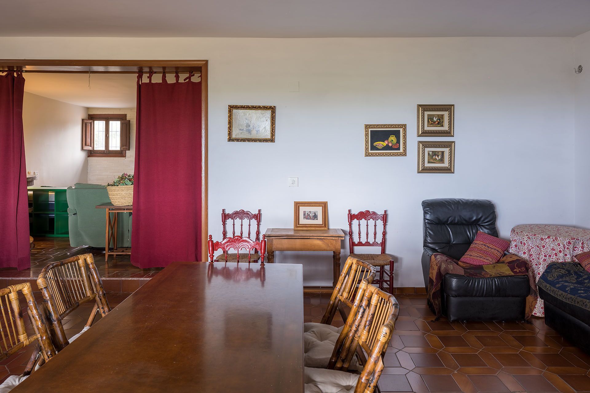 A dining area with a wooden table and chairs, a sofa, and a leather armchair.