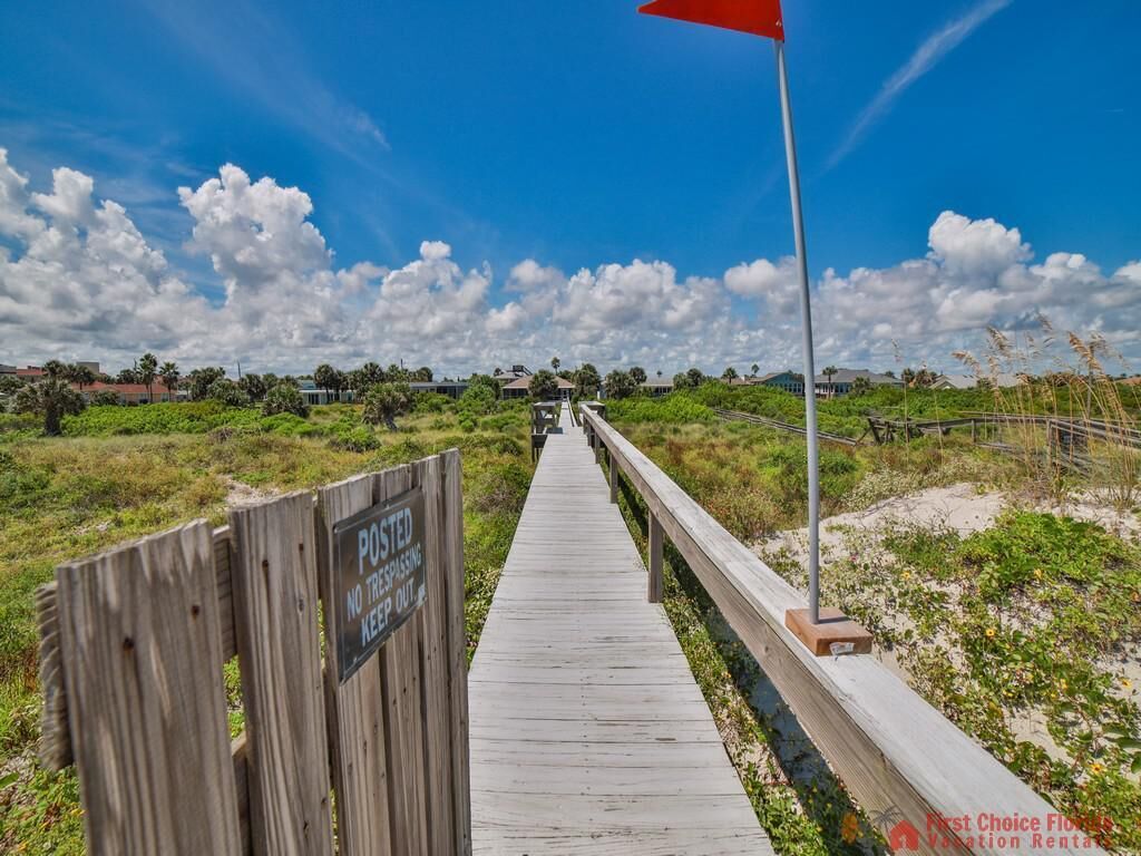 Un muelle de madera que lleva a una playa, con un letrero que indica 'No Trespassing'.