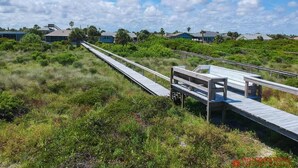 A wooden boardwalk leading to a beach area with houses in the background. - Direct Oceanfront ~ Private Walkway ~ Excellent Rates! (Saint Augustine)