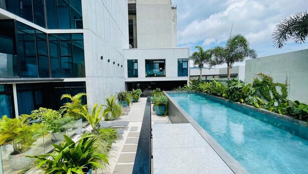 Un edificio moderno con piscina rodeada de plantas tropicales.