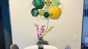 Un comedor moderno con una mesa redonda, dos sillas grises y un jarrón de flores.