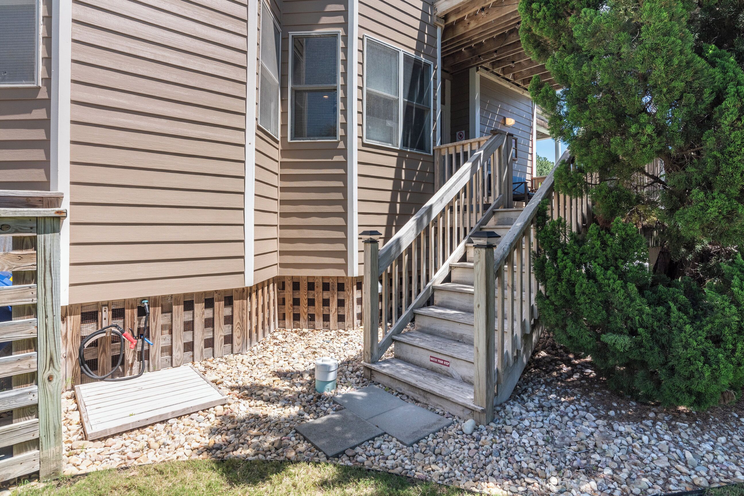A two-story house with a wooden staircase leading to the front door, a small porch area, and a bicycle parked outside.