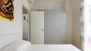 Un dormitorio con cama, armario y un cuadro en la pared.