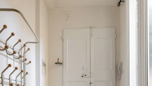 Un pasillo con suelo de madera, un perchero y una puerta blanca.