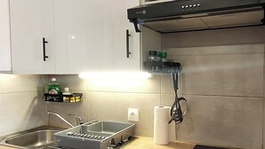 Een kleine keuken met een wasmachine, een magnetron en een fornuis.