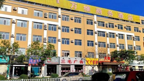 A multi-story hotel with a yellow facade and multiple air conditioning units on the exterior.