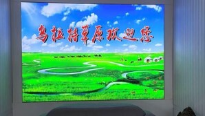 A large flat-screen TV displaying a scenic landscape with Chinese text.