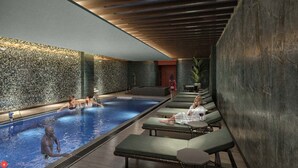 Un área de piscina con sillas de descanso y un muro de piedra.