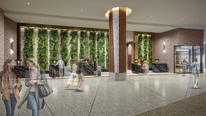Un vestíbulo con una recepción, un amplio jardín vertical y un escaparate de vidrio.