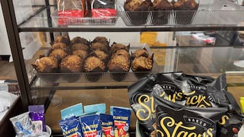 A display case with baked goods and snacks, including muffins, cookies, and pita chips.