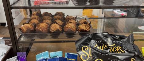 Une vitrine contenant des pâtisseries et des en-cas, notamment des muffins, des biscuits et des chips de pain pita.