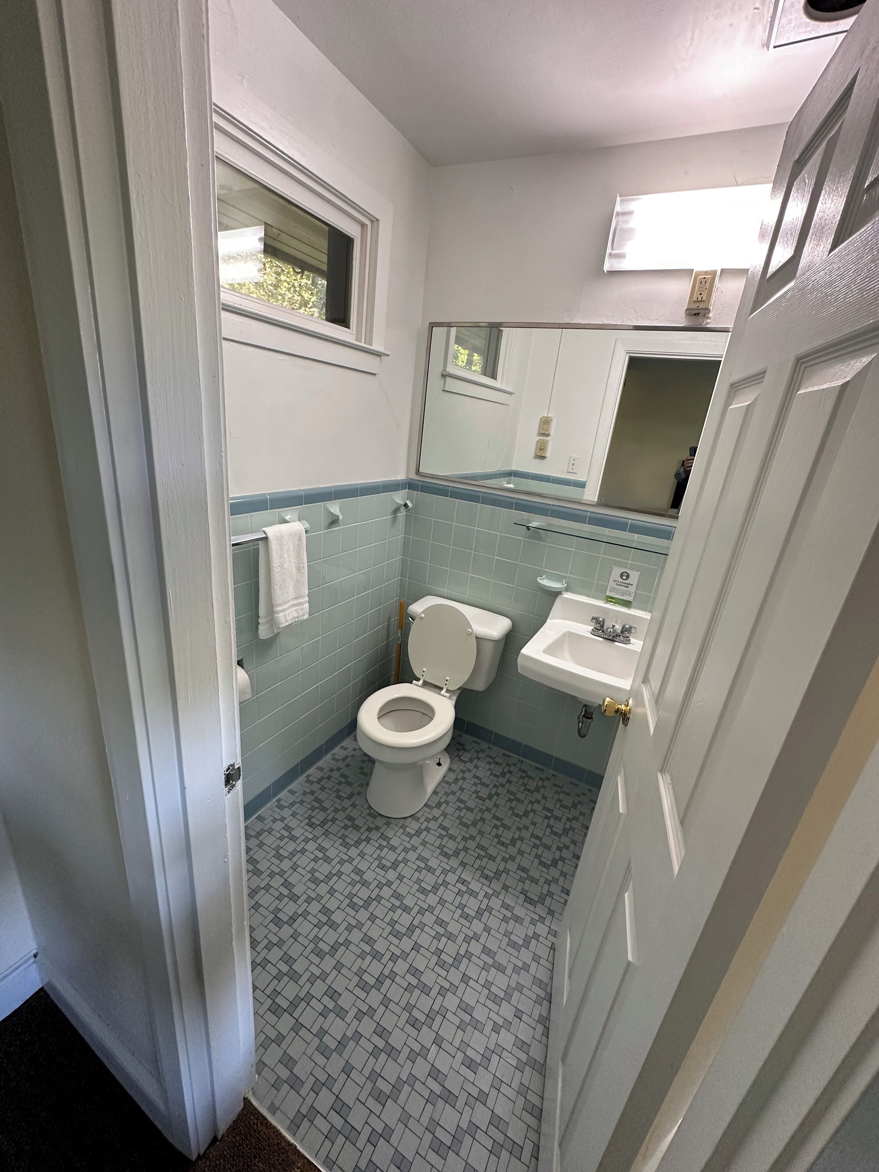 Een badkamer met toilet, wastafel en spiegel.