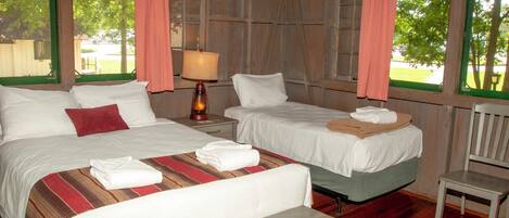 A room with two beds, a wooden table, and a chair.