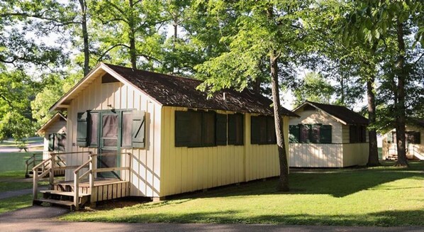 A row of small, single-story cabins with a simple, rustic design, each featuring a front porch and a small staircase leading to the entrance. - The Lodge at Mammoth Cave  (Brownsville)