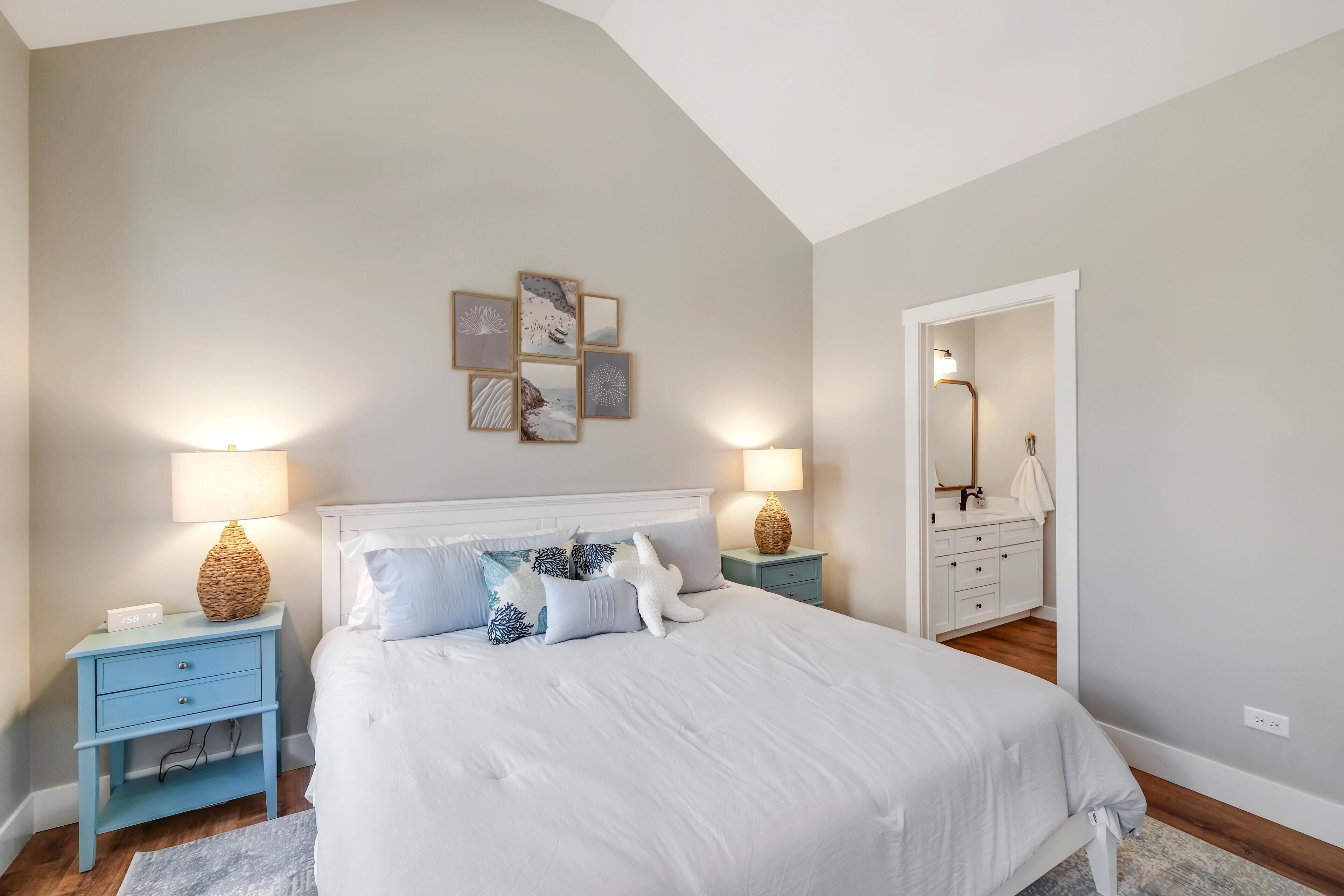 A bedroom with a large bed, two nightstands, a dresser, and a mirror.