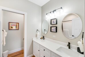 A bathroom with a white vanity, a large mirror, and a light fixture above the mirror. - Marina Tower (Ottawa)