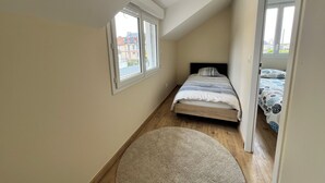 A narrow room with a bed, a window, and a door leading to another room. - Charming house with garden, harbour view, beach within walking distance (Dives-sur-Mer)