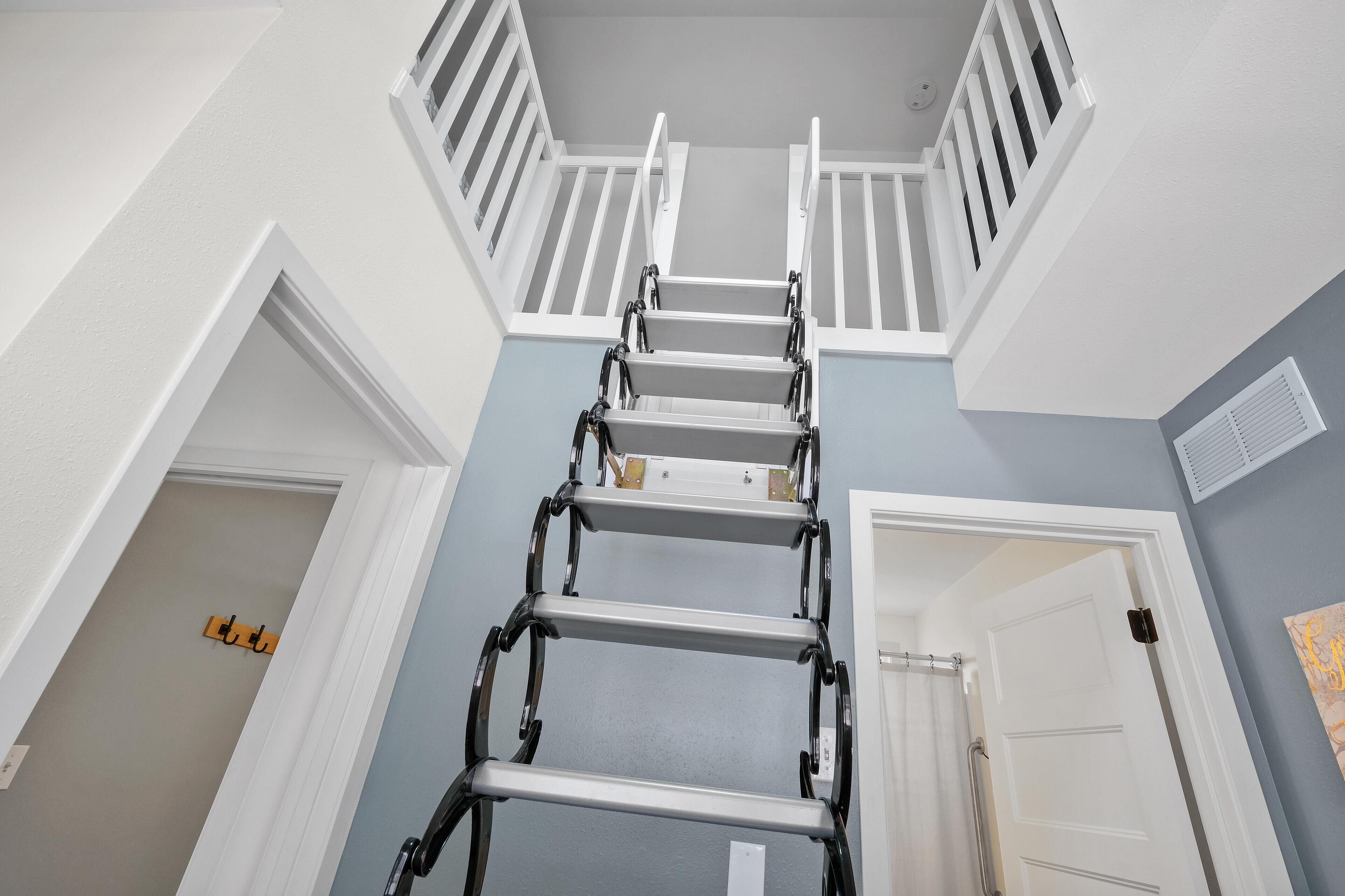 A multi-level interior with a metal ladder leading to a balcony.