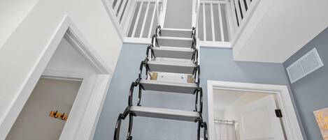 A multi-level interior with a metal ladder leading to a balcony.