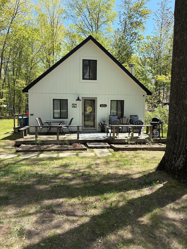 A white cabin with a porch, a grill, and a sign that reads 'Belle.'