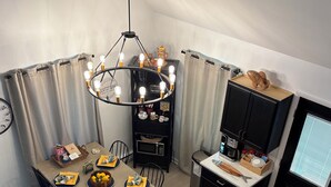 Una cocina compacta con comedor, un mueble negro con microondas, y una lámpara colgante.