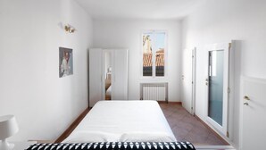 Une chambre à coucher avec un lit, un radiateur, une fenêtre et une porte.