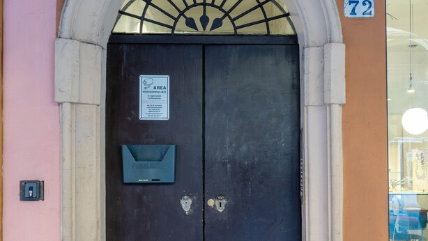 Une porte à deux battants, avec une pancarte indiquant un espace accessible aux personnes handicapées, une boîte aux lettres et le numéro « 72 » peint sur le mur.