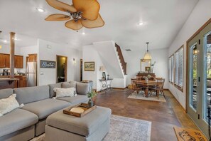 Un vaste espace de vie comprenant un canapé, une table à manger et un ventilateur de plafond.