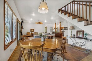A spacious living area with a dining table, chairs, and a staircase.