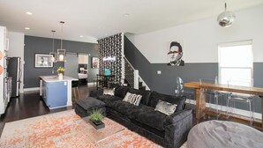 Un salon moderne avec un canapé noir, une table basse et un escalier menant à un autre niveau.